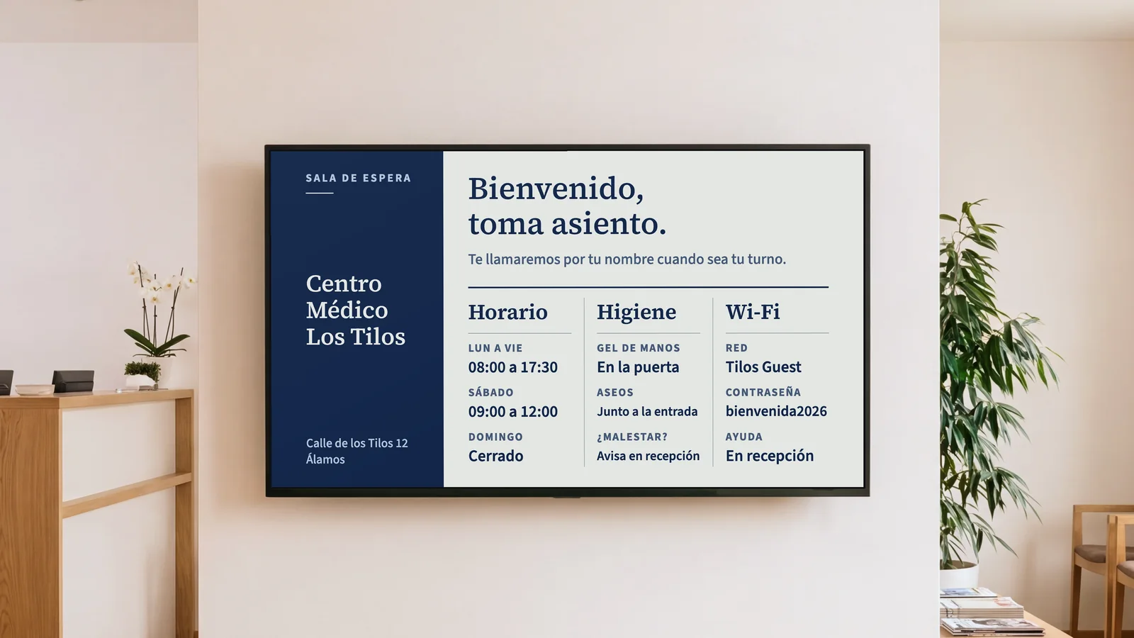 Sala de espera de una consulta con un rincón del mostrador de recepción, sillas de roble y una pantalla en una pared de blanco cálido. Muestra Centro Médico Los Tilos y Bienvenido, toma asiento, con horario, higiene, aseos y wifi debajo.
