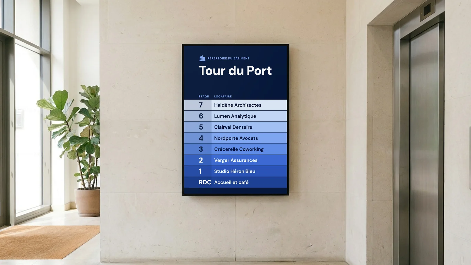 Hall d'un immeuble de bureaux avec un écran en portrait sur un mur en pierre calcaire claire, à côté des portes d'ascenseur en acier, avec une entrée vitrée et une plante à gauche. L'écran affiche le répertoire de la Tour du Port, avec Haldène Architectes et Accueil et café.