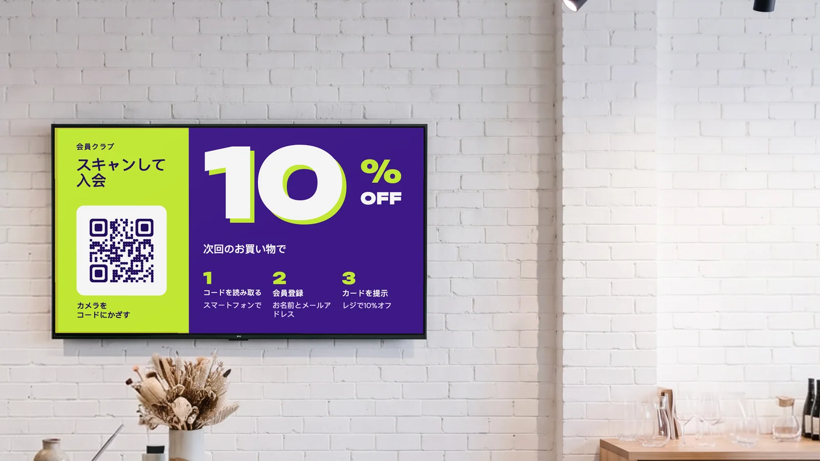 白いレンガの壁のレジ奥に画面がある雑貨店。テラゾーのカウンターにドライフラワー、脇の棚に陶器が並ぶ。画面には会員クラブの案内として、スキャンして入会、次回のお買い物で10%オフと表示されている。