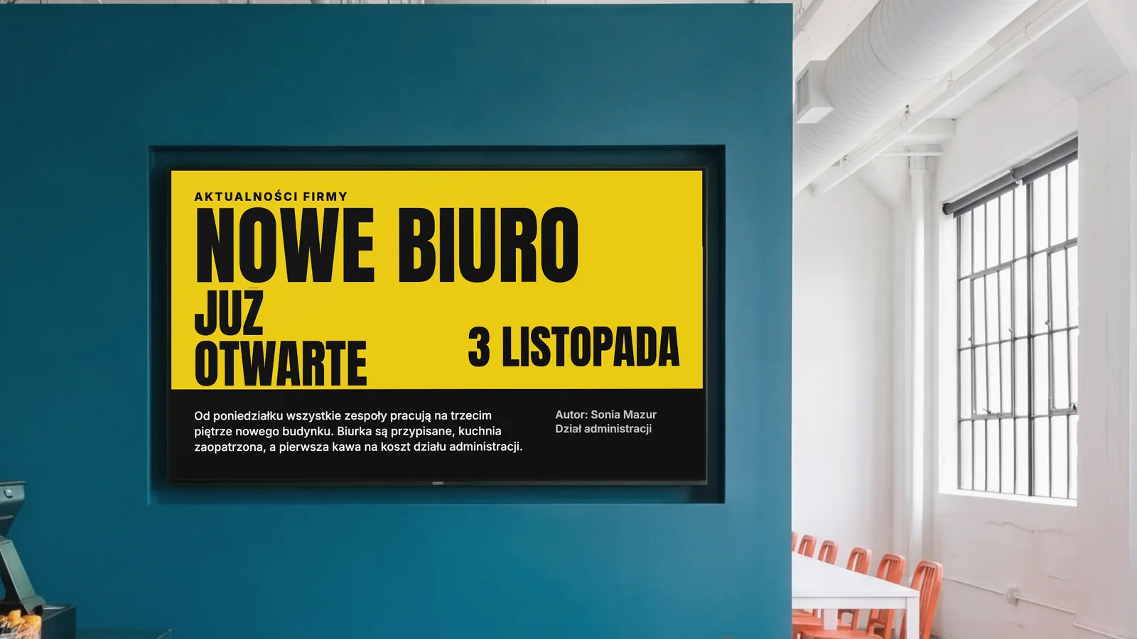 Stołówka firmowa z ekranem wpuszczonym w ciemnoturkusową ścianę, fragmentem lady i pomarańczowymi krzesłami po bokach. Ekran pokazuje Aktualności firmy: nowe biuro już otwarte, 3 listopada.