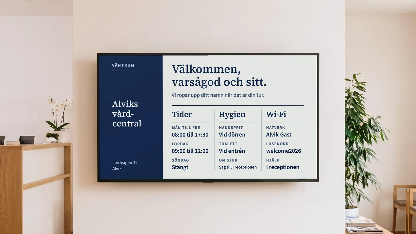 Väntrum på en vårdcentral med ett hörn av receptionsdisken, väntstolar i ek och en skärm på en varmvit vägg. Den visar Alviks vårdcentral och Välkommen, varsågod och sitt, med tider, hygien, toalett och wifi under.