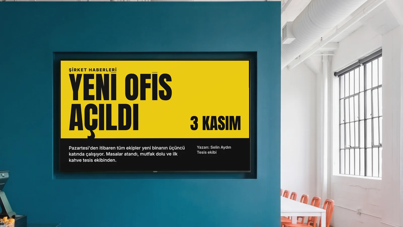 Koyu turkuaz bir duvara gömülü ekranı, tezgâhtan bir köşeyi ve yanlarda turuncu sandalyeleri gösteren bir personel yemekhanesi. Ekranda Şirket Haberleri yazıyor: yeni ofis açıldı, 3 Kasım.