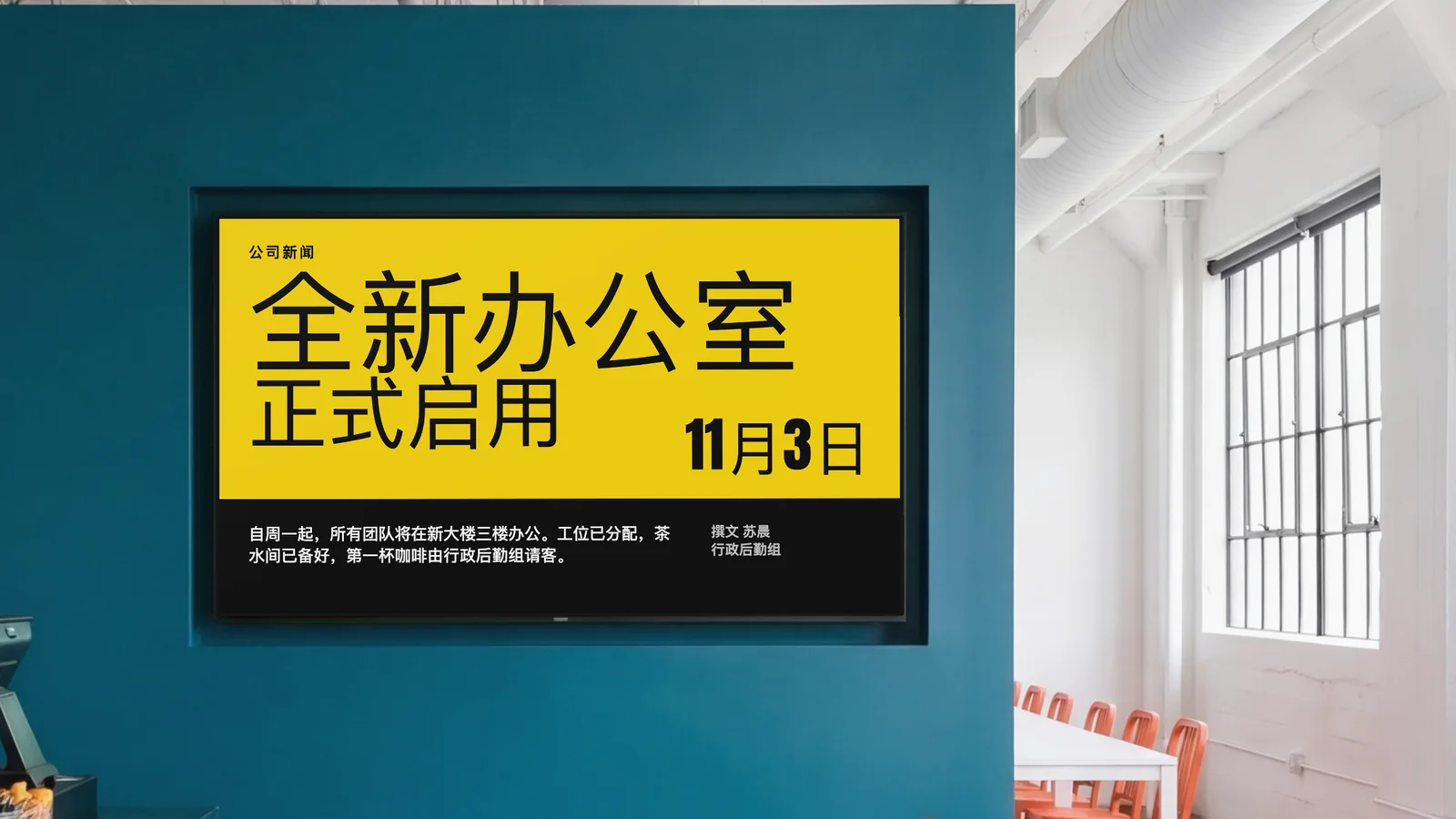公司员工食堂,屏幕嵌在深青色的墙里,两侧能看到柜台的一角和橙色椅子。屏幕显示公司新闻:全新办公室正式启用,11月3日。